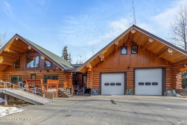 log home featuring a garage, driveway, and log siding