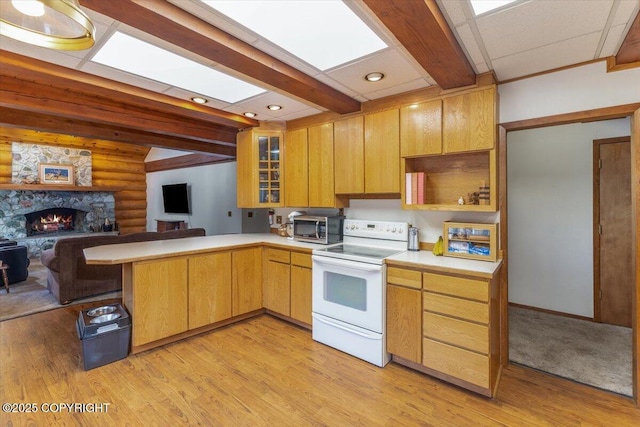 kitchen with light countertops, a stone fireplace, a peninsula, and white range with electric cooktop