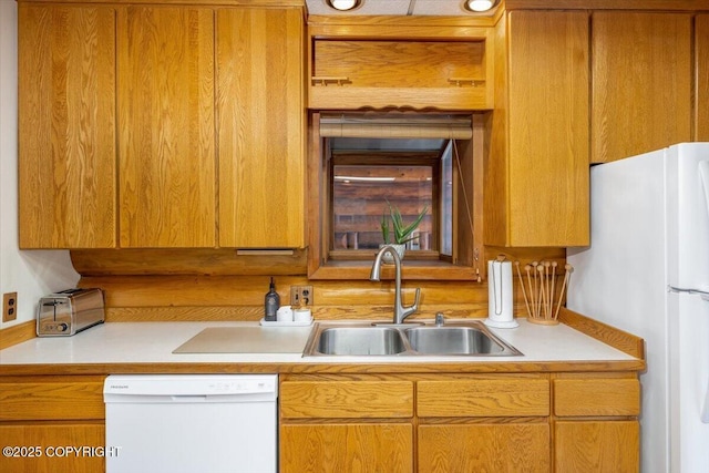 kitchen with light countertops, white appliances, and a sink