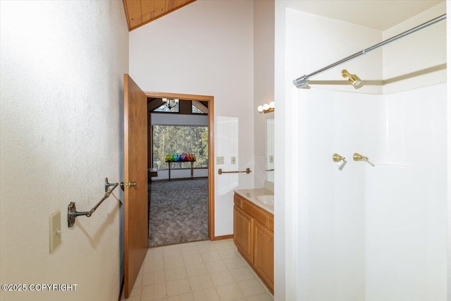 full bath featuring high vaulted ceiling, walk in shower, and vanity