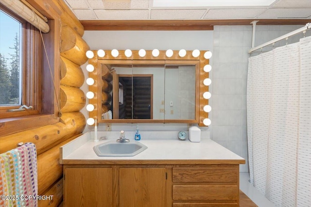 full bath featuring a wealth of natural light, curtained shower, rustic walls, and vanity