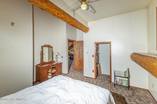 bedroom with a ceiling fan, carpet, a spacious closet, beam ceiling, and a closet