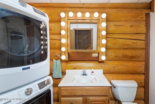 bathroom with toilet, stacked washer and dryer, and vanity