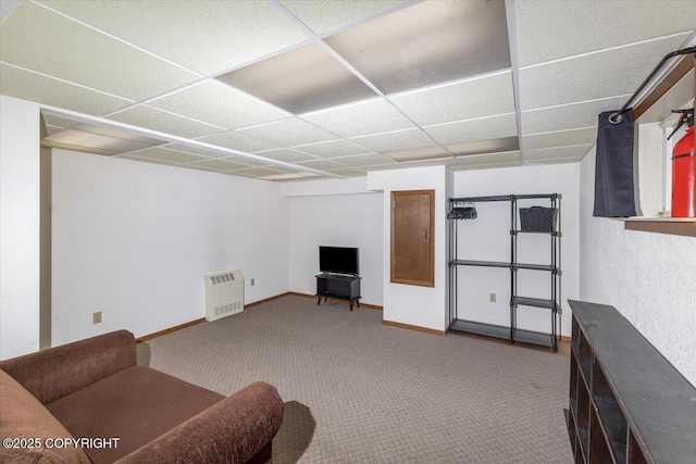 carpeted living area featuring baseboards and a drop ceiling