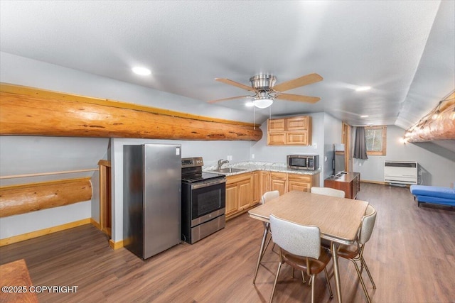 kitchen featuring appliances with stainless steel finishes, a sink, heating unit, and wood finished floors