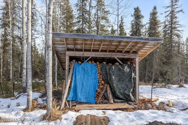 snow covered structure with an outbuilding and a wooded view