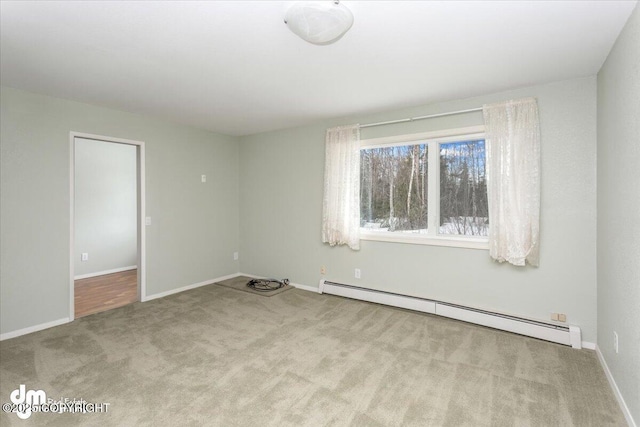 spare room featuring a baseboard heating unit, carpet, and baseboards