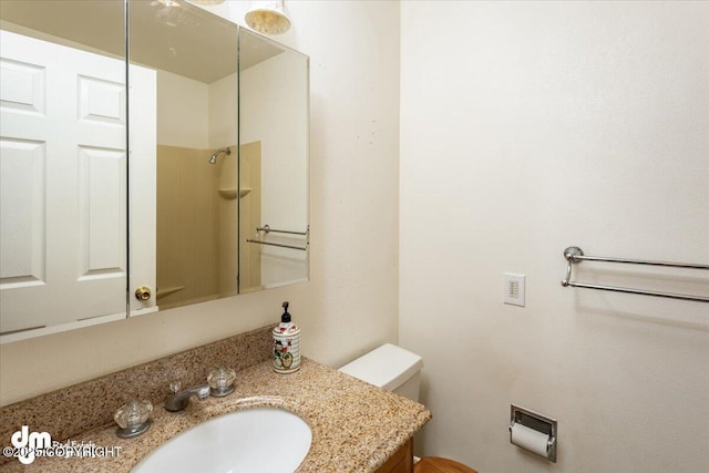 bathroom featuring toilet, a shower, and vanity