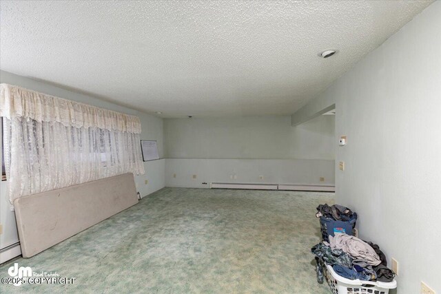 carpeted spare room featuring a baseboard heating unit and a textured ceiling