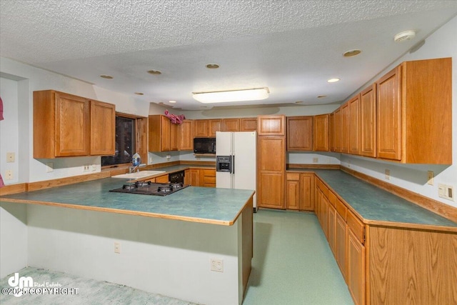 kitchen with white refrigerator with ice dispenser, brown cabinets, a peninsula, gas stovetop, and black microwave