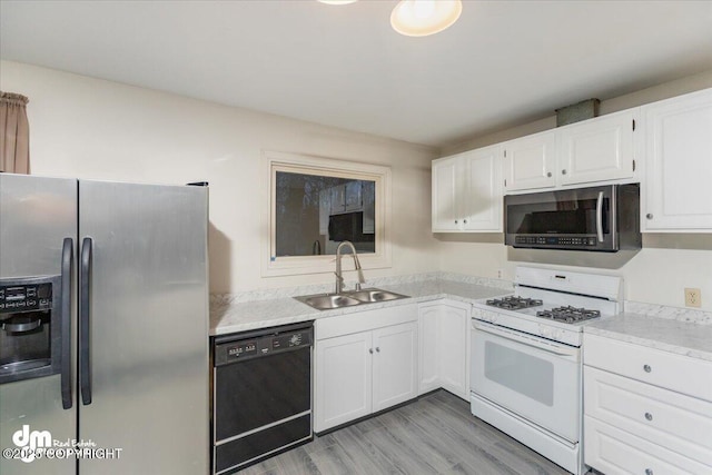 kitchen featuring stainless steel appliances, light countertops, light wood-style floors, white cabinetry, and a sink