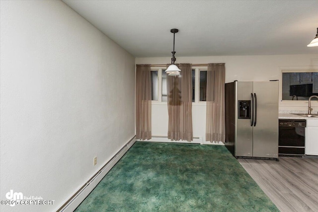 unfurnished dining area with baseboards, baseboard heating, a sink, and light wood-style floors