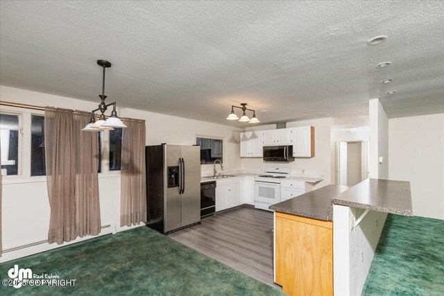 kitchen featuring dark wood-style floors, appliances with stainless steel finishes, white cabinetry, a baseboard heating unit, and a sink