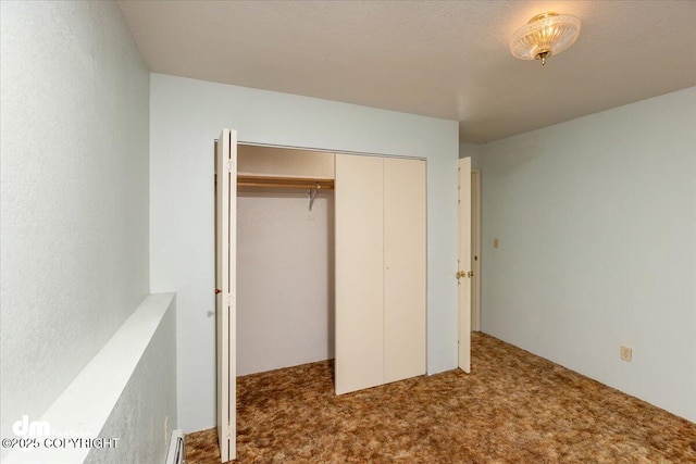 unfurnished bedroom featuring carpet floors, a baseboard heating unit, and a closet