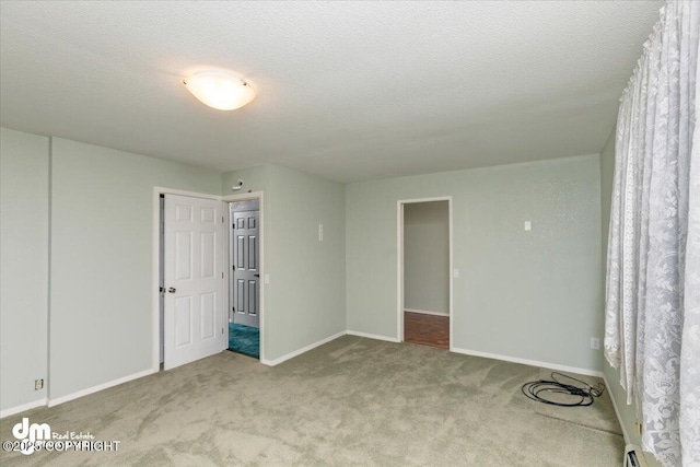 carpeted spare room featuring baseboard heating, a textured ceiling, and baseboards