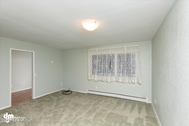 spare room featuring carpet floors, a baseboard radiator, a textured ceiling, and baseboards