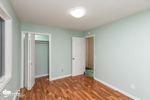 unfurnished bedroom with a closet, baseboards, and wood finished floors