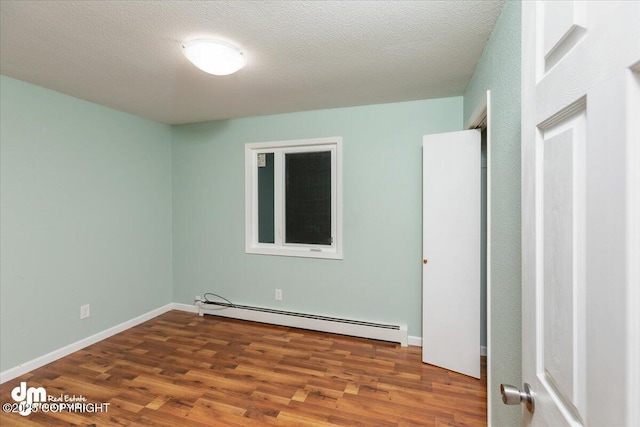 unfurnished bedroom with a baseboard radiator, a textured ceiling, and wood finished floors