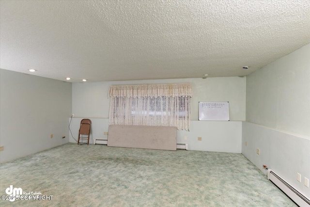 carpeted spare room with baseboard heating and a textured ceiling