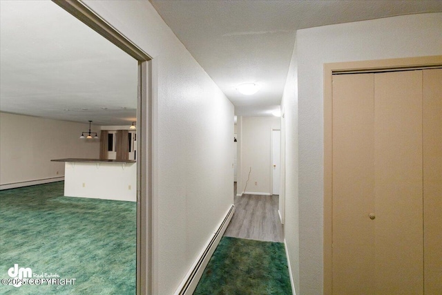 corridor featuring a baseboard heating unit, carpet, and baseboards