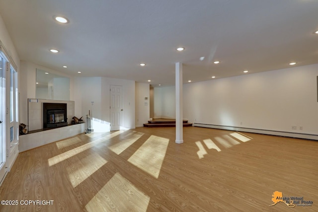 unfurnished living room with recessed lighting, a tile fireplace, light wood finished floors, baseboards, and baseboard heating