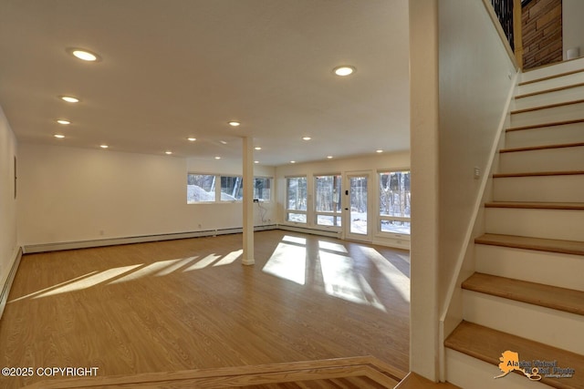 basement featuring stairway, wood finished floors, baseboard heating, and recessed lighting