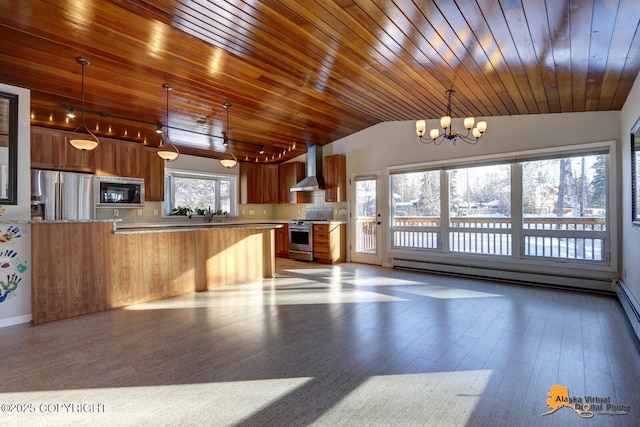 kitchen with wall chimney range hood, vaulted ceiling, stainless steel appliances, light countertops, and a notable chandelier
