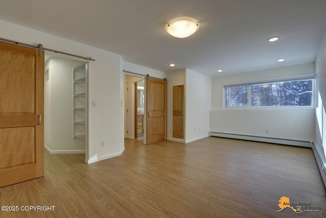 interior space with a barn door, a baseboard heating unit, light wood finished floors, baseboards, and recessed lighting