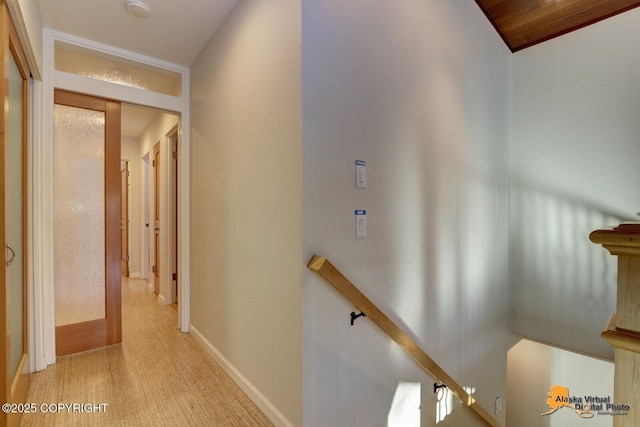 hall with light carpet, baseboards, and an upstairs landing
