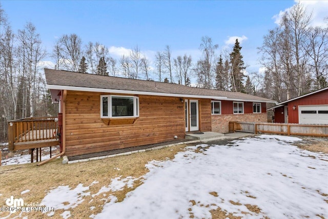 view of front of house with a wooden deck, fence, and an outbuilding