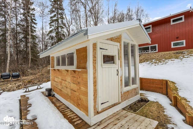 snow covered structure featuring an outbuilding