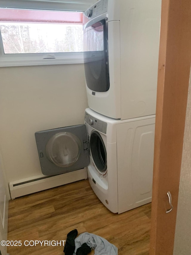 laundry area featuring stacked washer / drying machine, light wood-type flooring, and cabinet space