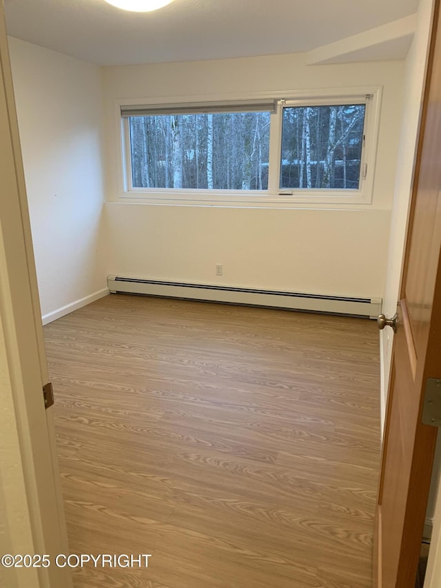 empty room with baseboard heating, baseboards, and wood finished floors