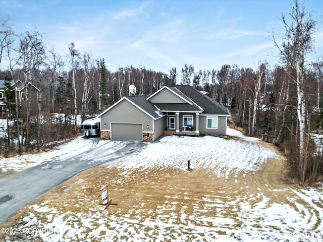 view of front of property featuring a garage, a view of trees, and stone siding