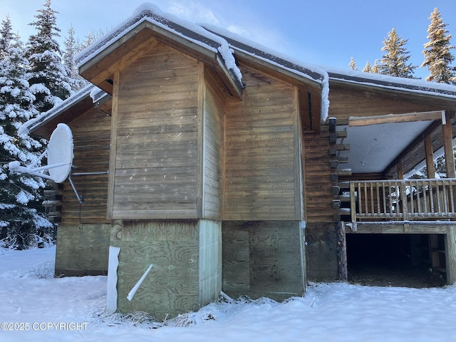 view of snowy exterior featuring log siding