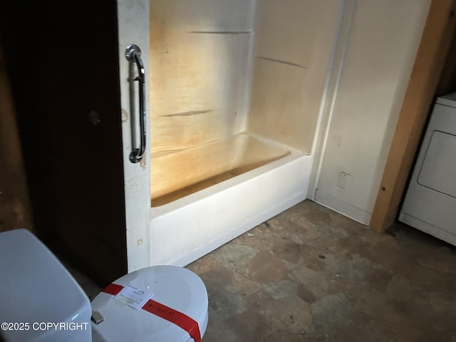 bathroom featuring toilet and washer / clothes dryer