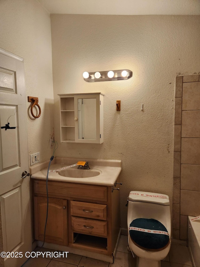 bathroom with a textured wall, tile patterned flooring, a bathtub, and vanity