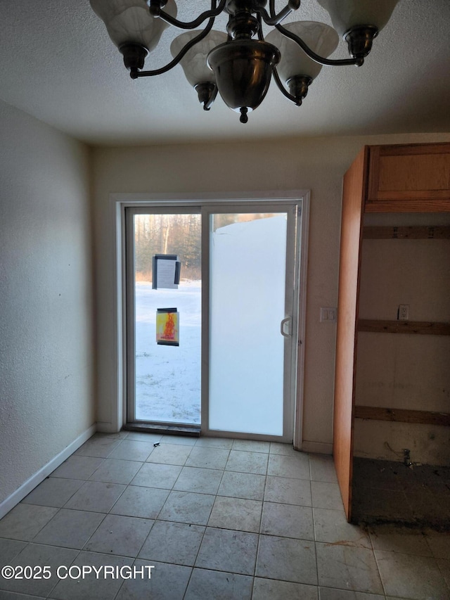 doorway to outside featuring a textured ceiling, baseboards, and light tile patterned floors