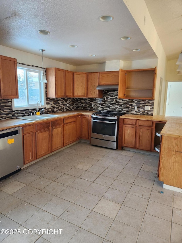 kitchen featuring decorative backsplash, appliances with stainless steel finishes, light countertops, open shelves, and a sink