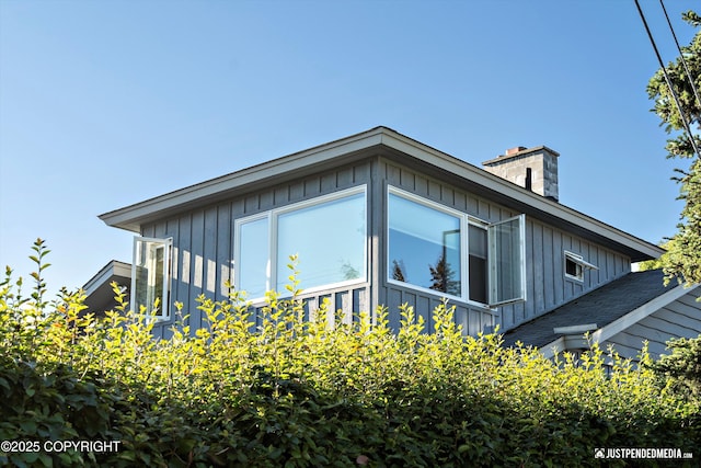 view of side of home with a chimney and board and batten siding