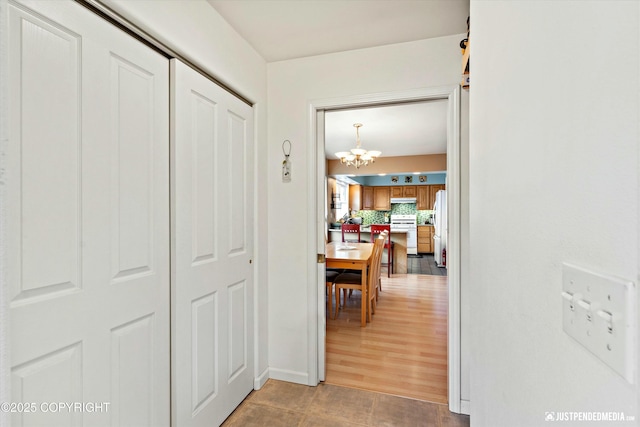 corridor with a notable chandelier and baseboards