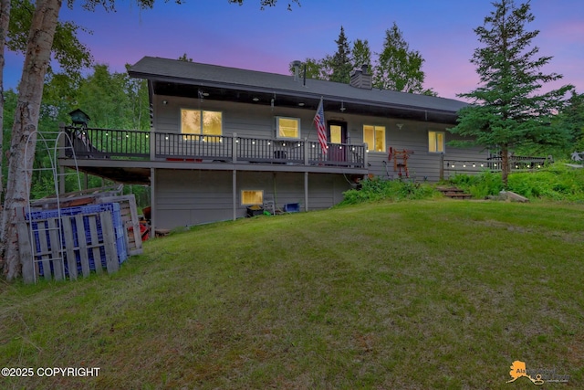 back of house featuring a deck, a lawn, and a chimney