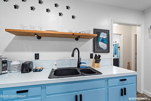 521 N St, Anchorage, AK 99501 - kitchen with light countertops, a sink, open shelves, stainless steel microwave, and blue cabinetry