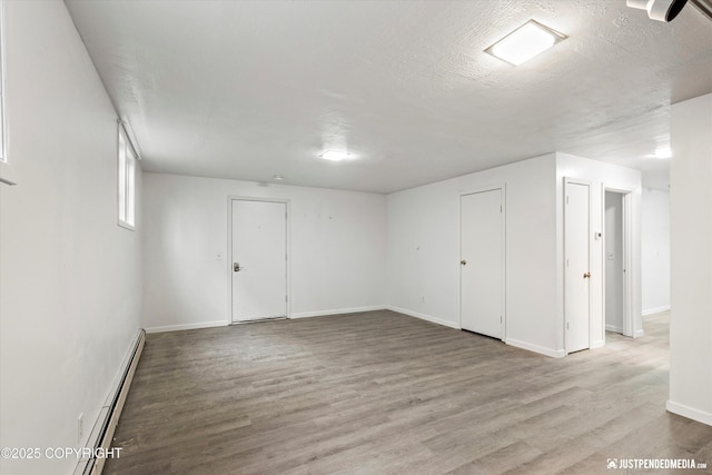 521 N St, Anchorage, AK 99501 - below grade area featuring baseboards, a textured ceiling, wood finished floors, and a baseboard radiator