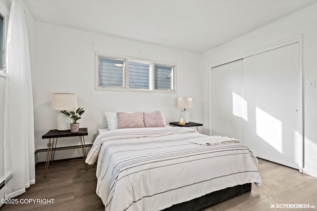 521 N St, Anchorage, AK 99501 - bedroom featuring wood finished floors, baseboards, a closet, and baseboard heating