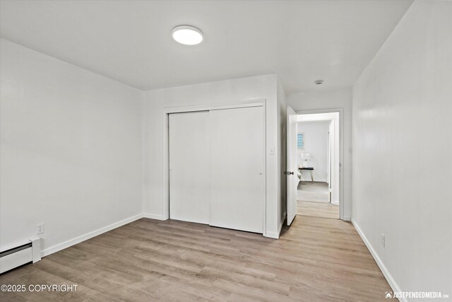 521 N St, Anchorage, AK 99501 - unfurnished bedroom featuring a baseboard radiator, light wood-style flooring, baseboards, and a closet