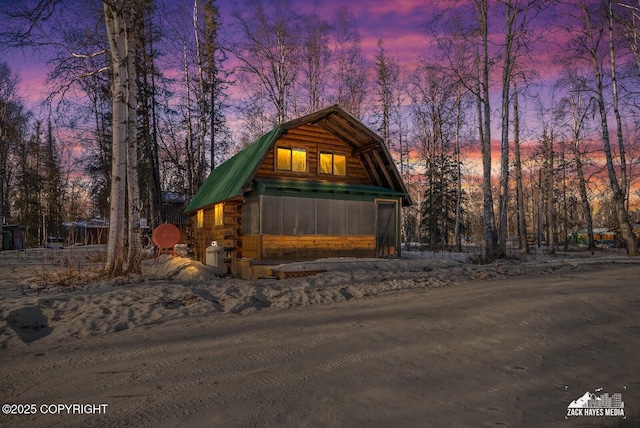 view of front of house featuring metal roof, a gambrel roof, and log siding