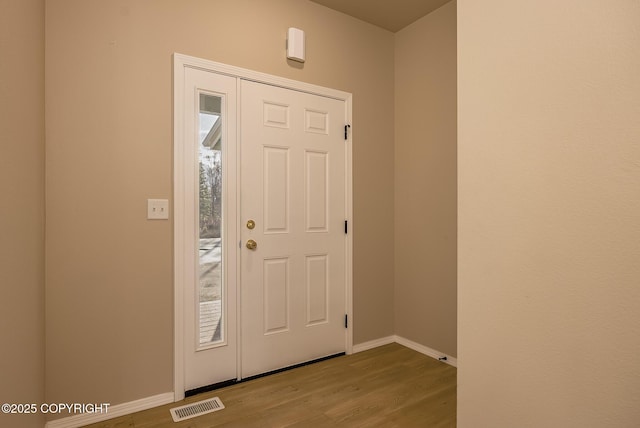 foyer featuring a wealth of natural light, wood finished floors, visible vents, and baseboards