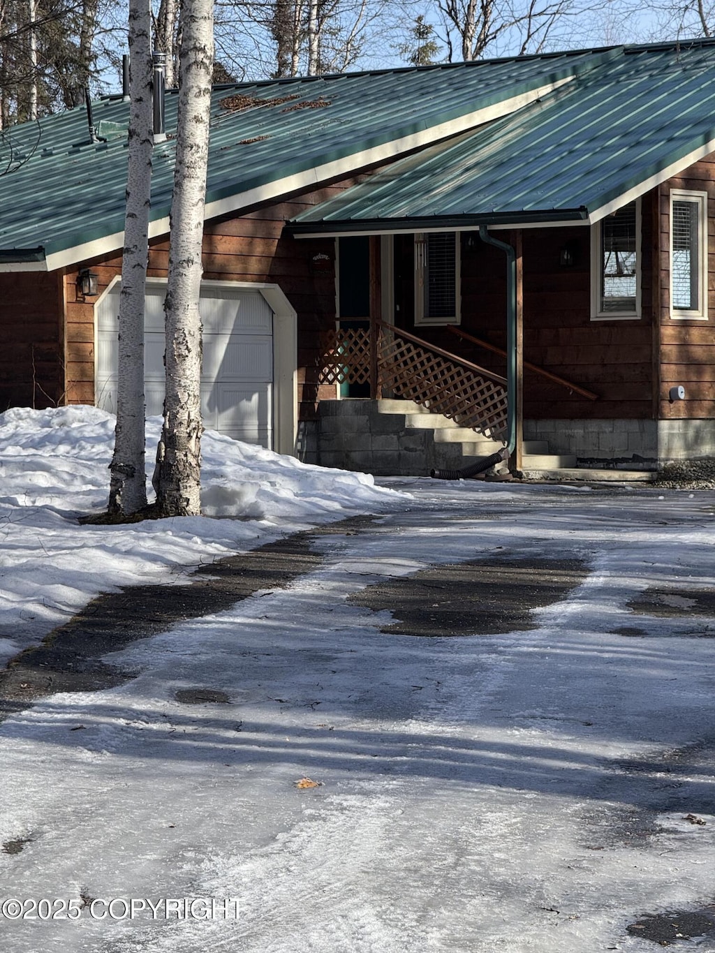 view of side of property featuring a garage, metal roof, and driveway