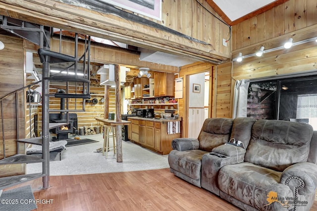 living area featuring a wood stove, wooden walls, and light wood finished floors